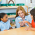 Adult teacher with two students looking into a Cup of Caterpillars